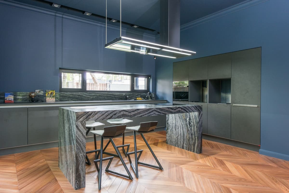 Navy kitchen cabinetry with a stone island and brass fixtures
